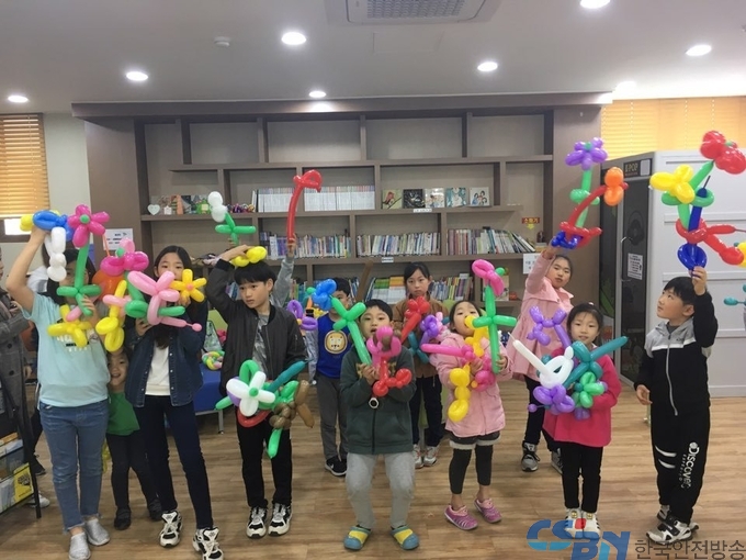 초등학생들이 내가만든 요술풍선을 들고 단체사진을 찍고있다.